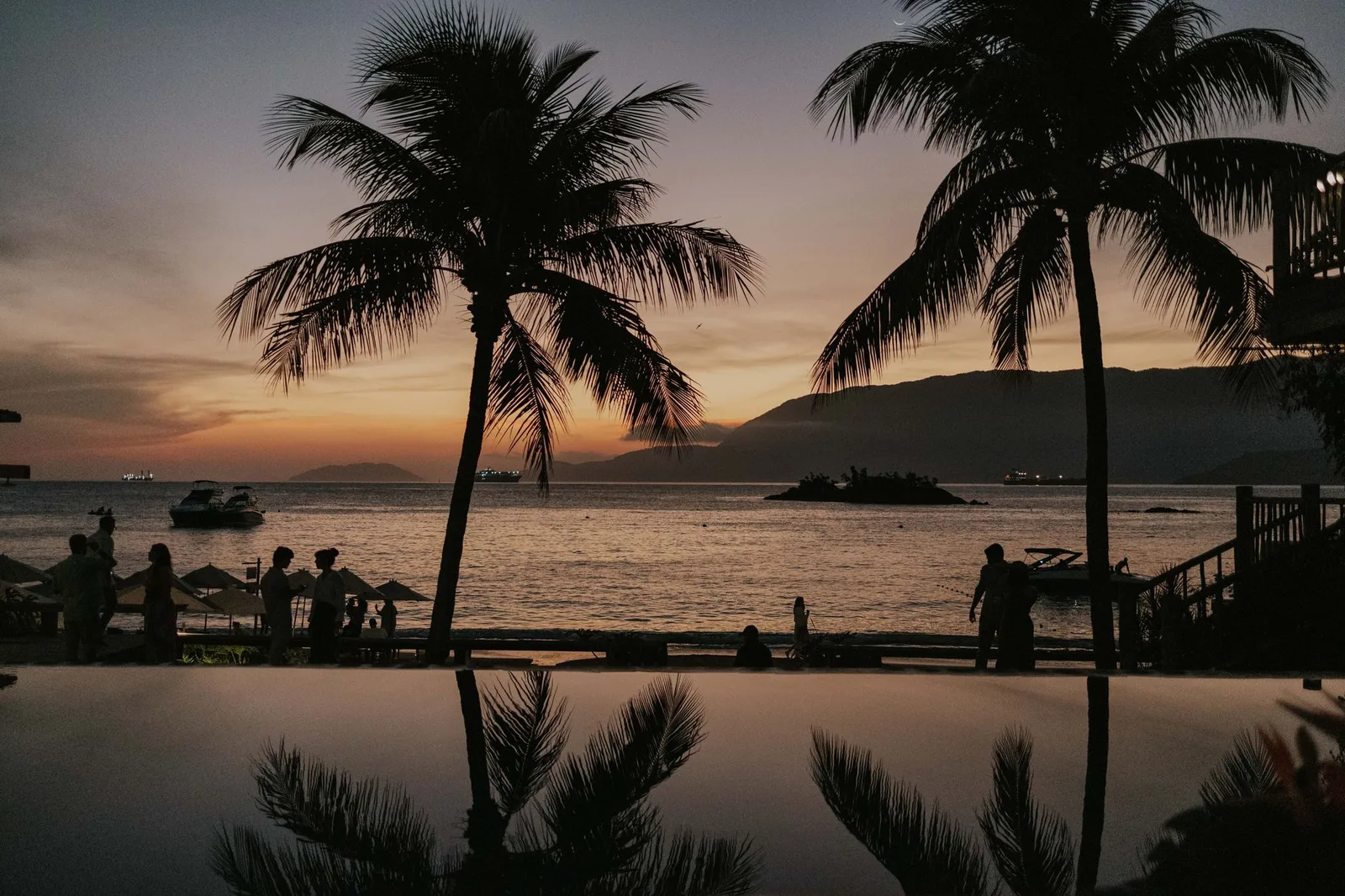 Scenic tropical sunset with palm trees and silhouettes by the sea, perfect for travel imagery.