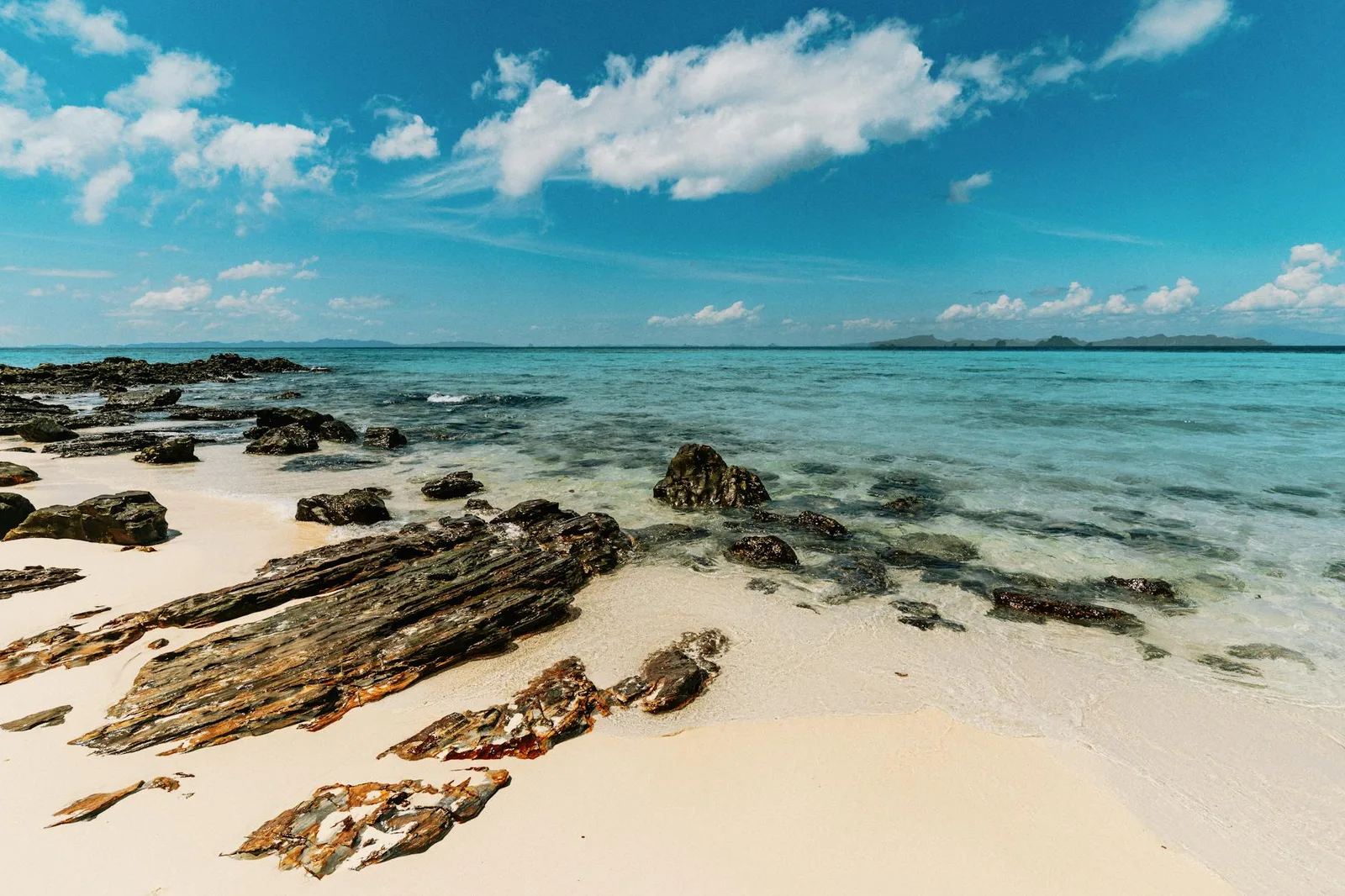 Tranquil beach with rocks and turquoise waters in Ao Nang, Krabi, Thailand.